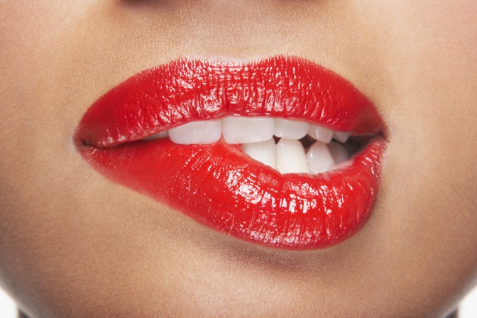 Eine Frau beißt sich in die roten Lippen