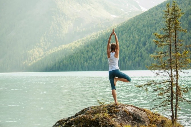 Eine Frau macht Yoga an einem See.
