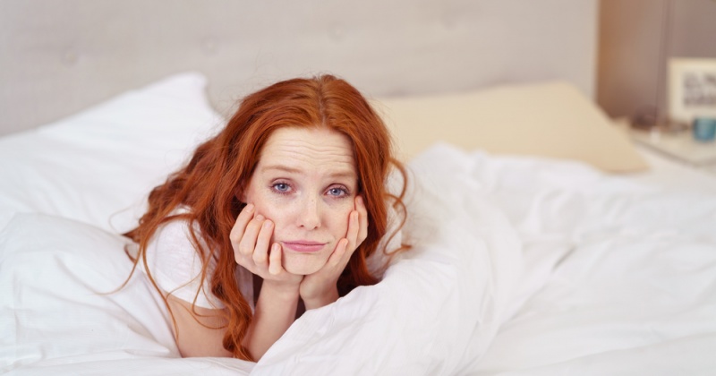Eine Frau im Bett kämpft mit Abgeschlagenheit