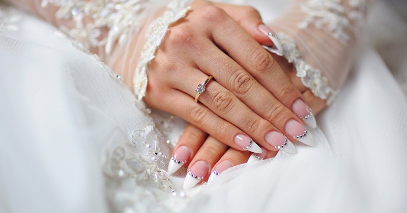 Braut im Hochzeitskleid mit Strasssteinen auf den Fingernägeln