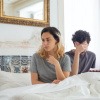 Unglückliche Frau neben Mann im Bett