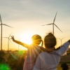 Frau und Mädchen vor nachhaltigen Windrädern im Sonnenuntergang