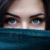Frau mit schönen und gesund wirkenden Augen sieht hinter einem Schal hervor