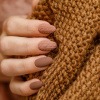 Finger mit Nagellack in Nagellack-Trend braun