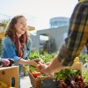 Frau kauft am Markt regionales Gemüse als Ernährungstrend 2024