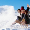 Mann und Frau beim Rodeln, einer Sportart im Winter