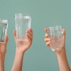 Hände halten Gläser mit Trinkwasser in die Luft