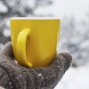 Frau mit Hanschuhen im Winter hält Teetasse in der Hand