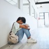 Mädchen sitzt wegen Prüfungsangst verzweifelt am Boden einer Schule