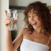 Frau mit einem Glas Wasser lächelt