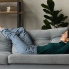 Frau liegt entspannt auf einem Sofa