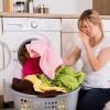 Frau nimmt muffig riechende Wäsche aus der Waschmaschine