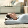 Am Boden liegende Frau hört Musik mit Kopfhörern, um zur Ruhe zu kommen