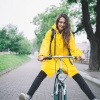 Eine Frau mit Regenhose und Regenjacke fährt mit dem Fahrrad