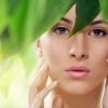 Ein hübsches Frauengesicht hat grüne Blätter im Vordergrund