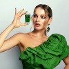 Frau mit einem Glas grünem Saft in der Hand