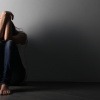 Eine traurige junge Frau will ihre Angst vor Ablehnung überwinden, kauert jedoch depressiv in einer Ecke.