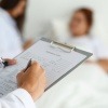 Ein Arzt schreibt eine Diagnose auf ein Datenblatt