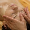Eine Frau liegt bei einer Ayurveda Kur und erhält eine Ölmassage auf der Stirn