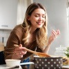 Frau beim Kochen genießt Duft der Speisen