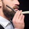 Ein Mann will sich seinen Bart richtig rasieren und stutzt seinen Vollbart dazu zunächst mit einer Bartschere.
