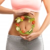 Junge Frau mit einem Kreis aus Gemüse vor dem Bauch
