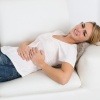Eine Frau mit Darmproblemen im Sommer liegt auf einer Couch