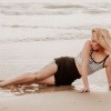 Eine Frau liegt am Strand, ihre Oberschenkel sind ohne sichtbare Cellulite