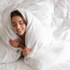 Bett wärmen - Frau eingekuschelt in ihrer warmen Bettdecke.
