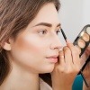 Das Gesicht einer Frau wird mit Camouflage Make-up geschminkt