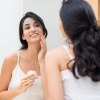 Eine Frau gibt Creme gegen Falten durch trockene Haut in ihr Gesicht