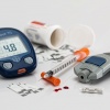 Ein Blutzuckermessgerät für Diabetes liegt neben Spritze und Messstreifen