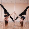 Zwei Frauen an der Pole Dance Stange. 