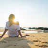 Eine Frau sitzt entspannt am Meer