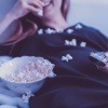 Eine Frau isst Popcorn während sie Fernsehen schaut
