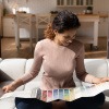 Eine lachende Frau sitzt auf der Couch und schaut sich verschiedene Farben an