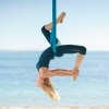 Eine junge Frau betreibt Flying Yoga am Meer