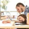 Eine Frau und ein Mann sind müde vom Arbeiten am Laptop