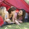 Drei Frauen liegen bei einem Frauencamp in einem Zelt