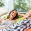 Ein frisch verliebtes Paar sitzt lachend auf dem Sofa