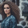 Eine Frau trägt als Trendfrisur 2021 naturkrause Haare