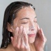 Eine Frau wäscht ihr Gesicht mit Seife