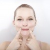Eine Frau betreibt Gesichtsgymnasitk gegen Hängebacken