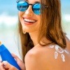 Eine Frau hat Sonnencreme in der Hand für die Gesichtspflege mit UV Schutz