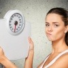 Eine Frau hält eine Waage und muss den Gewichts- und Stoffwechsel optimieren