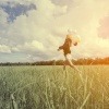 Eine Frau läuft mit Ballons durchs Feld und will glücklich sein