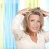 Eine Frau mit Haarausfall in den Wechseljahren rauft sich die Haare
