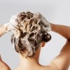 Eine Frau wäscht mit Silbershampoo ihre Haare gegen Gelbstich