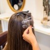 Frau beim Friseur bekommt Haarverdichtung mit Ultraschall