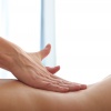 Eine Hand massiert bei einer erotischen Massage einen nackten Rücken